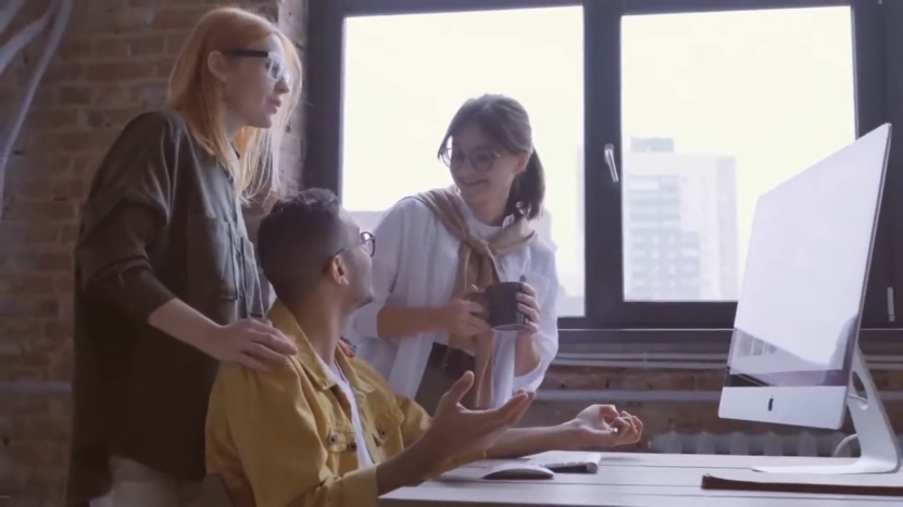 Colleagues Discuss Ideas Around a Computer in A Office