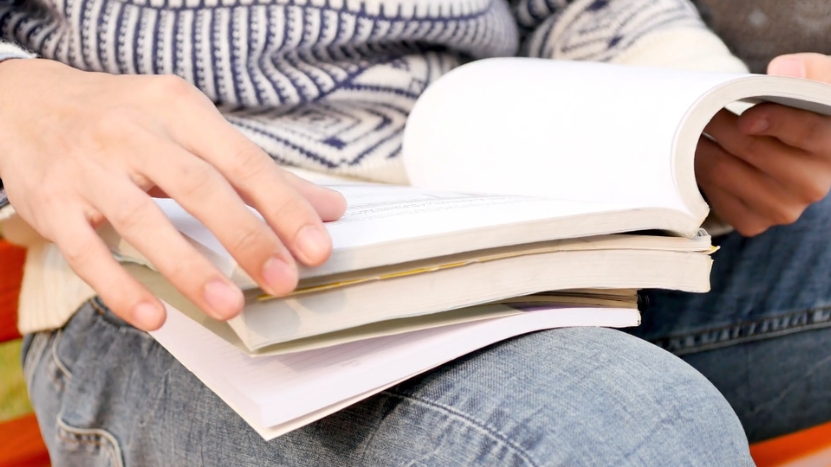 A person flipping through textbooks while studying