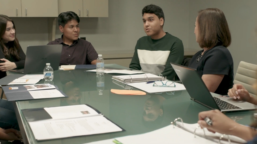 A Group of Students and Staff Engage in A Discussion Around a Table During a Meeting