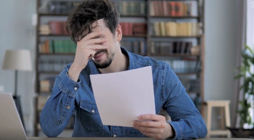 A man's reaction to difficult information while holding a paper document