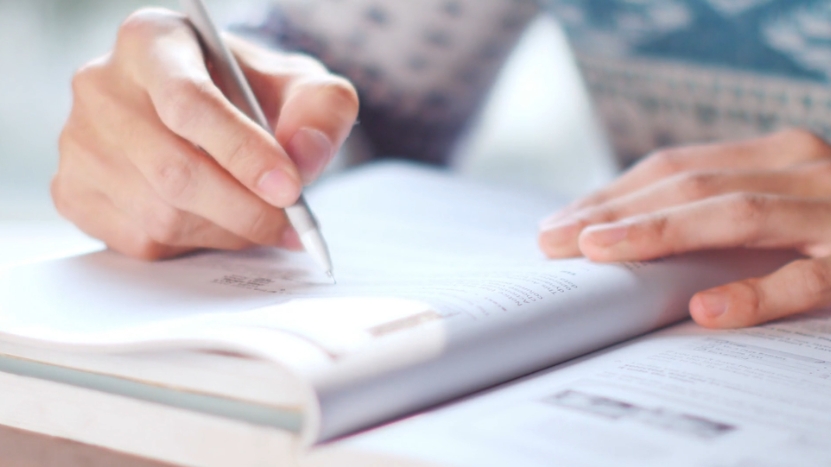 A person taking notes in a book to reinforce learning