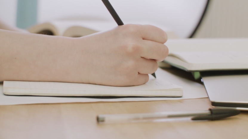 A Person Writing in A Notebook, Preparing a Letter of Recommendation Request