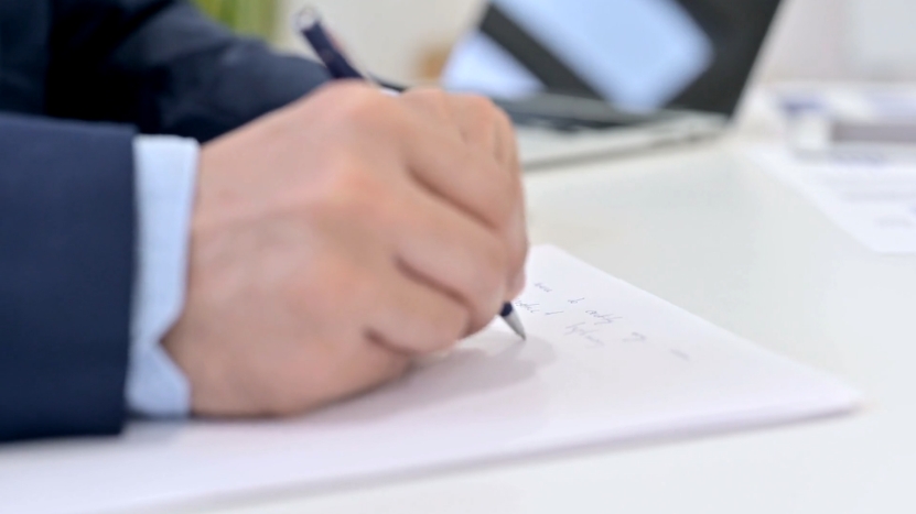 A Person Writing on A Piece of Paper with A Pen