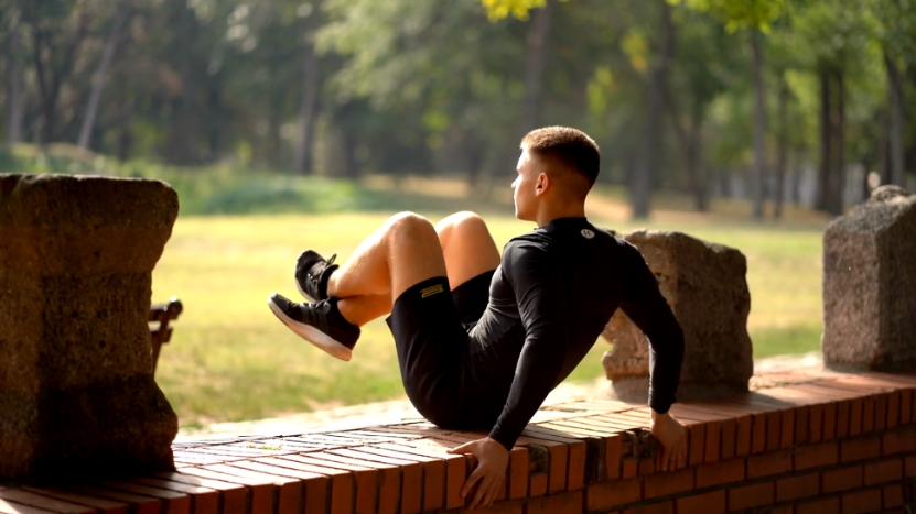 A person is performing outdoor exercises on a brick wall in a park