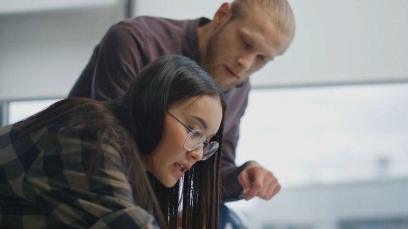 Two students collaborating while reviewing documents at a desk