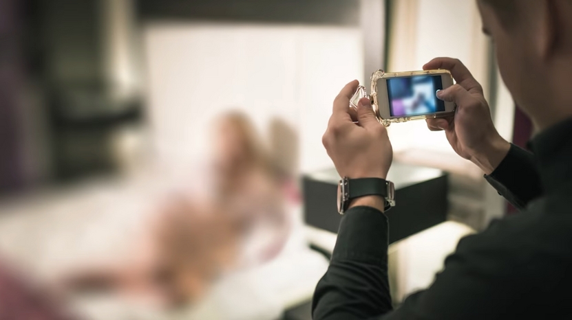 A man takes a photo of a blurred woman without consent, highlighting what the Take It Down Law now treats as a federal offense