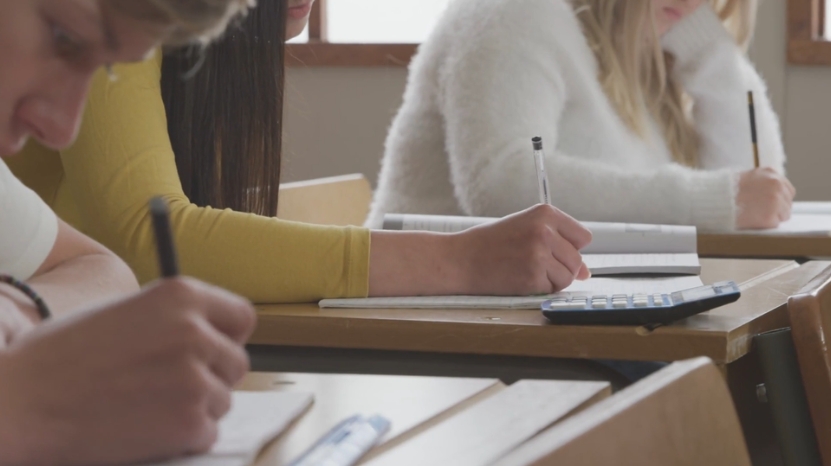 Students write in notebooks during class, showing active participation and helping ensure students use their work for in-class learning