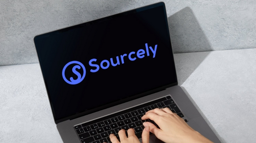 Hands typing on a laptop with the Sourcely logo displayed on the screen
