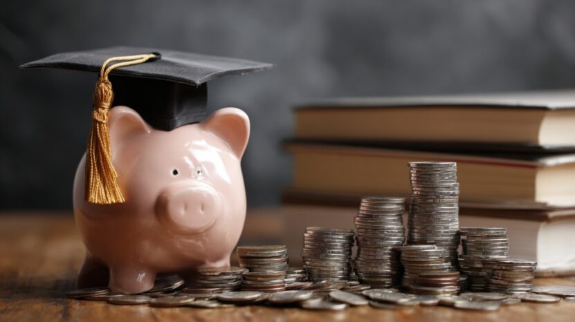 Piggy bank wearing a graduation cap next to stacks of coins and books