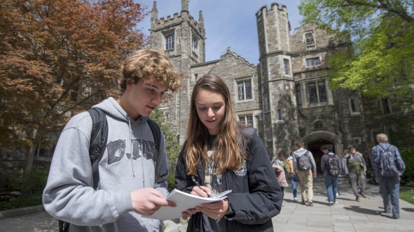 Two students reviewing notes while visiting a college campus