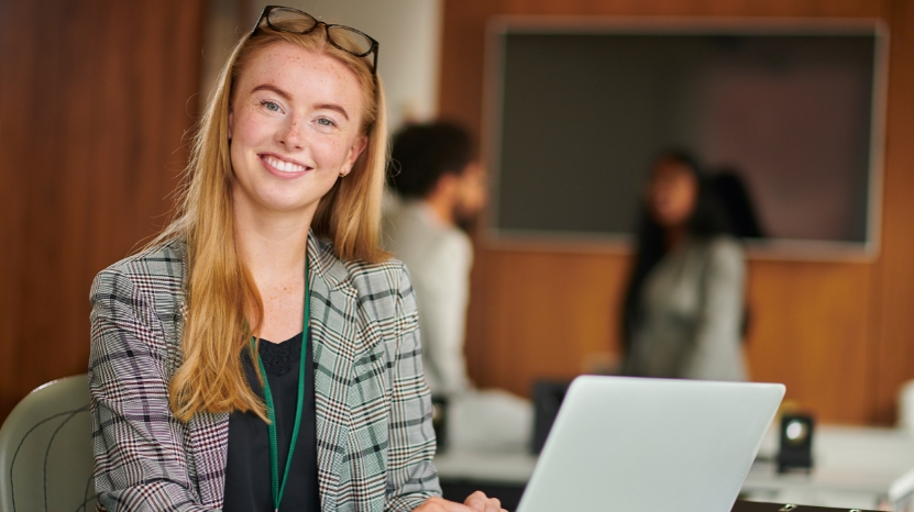 A young professional smiles at her laptop while gaining work experience before graduation