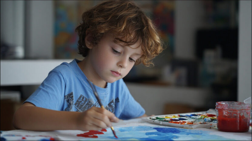 Young boy painting with bright colors, concentrating on his artwork