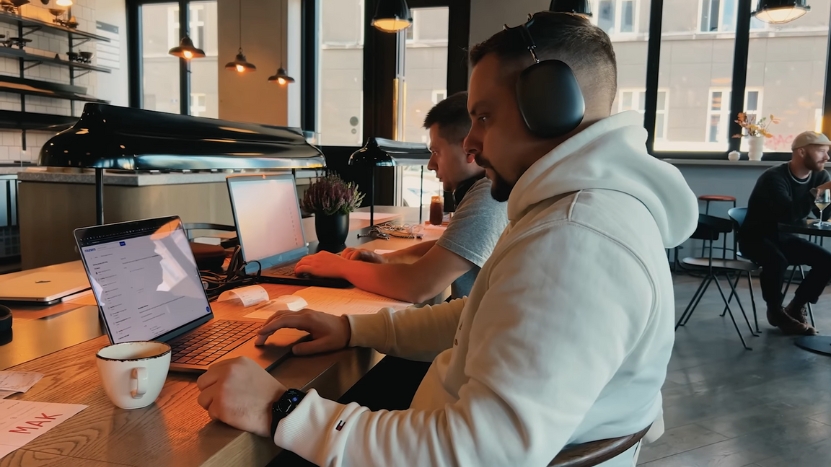 A man with headphones works on a laptop in a shared space, showing project-based learning on Skillshare