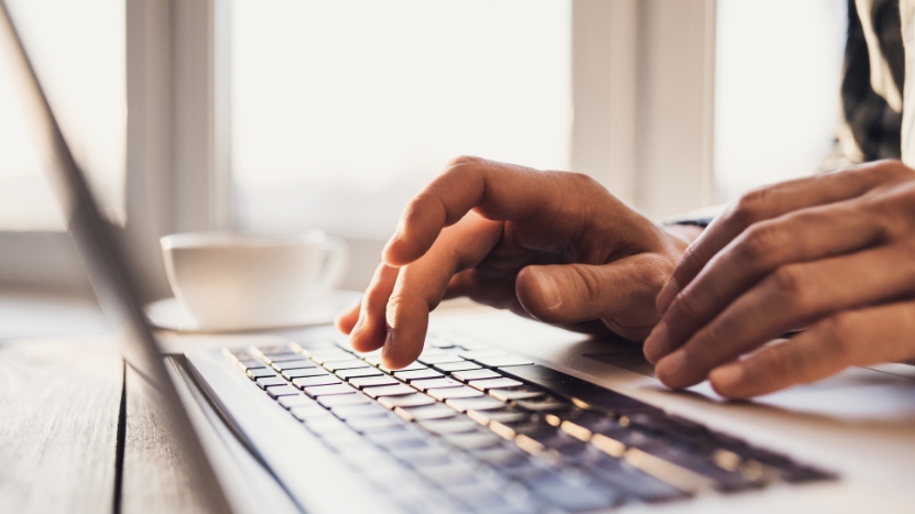 Close-up of a teacher’s hands typing on a laptop