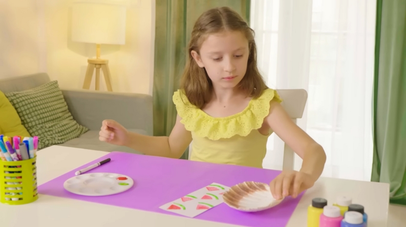 Young girl sitting at a table doing an arts and crafts project with paints and markers