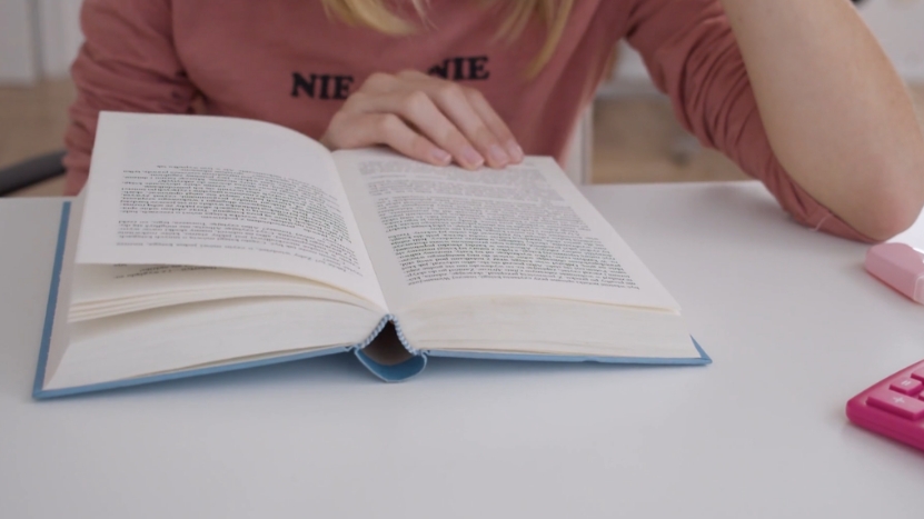 A student reads an open book at a desk during study time
